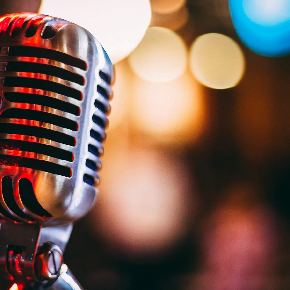 Placeholder: a vintage microphone in front of blurred stage lights.