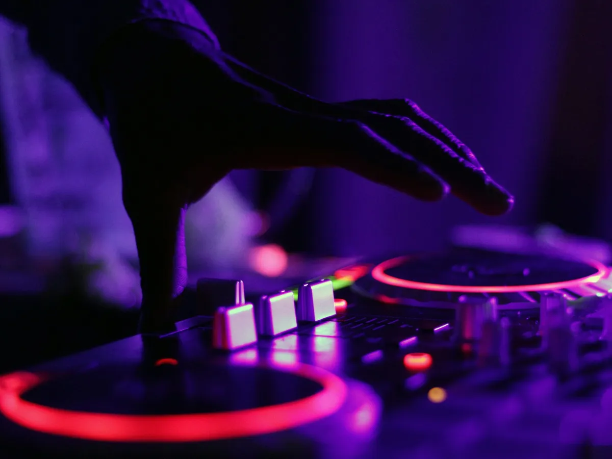 Placeholder: a hand on a DJ controller lit purple and red.