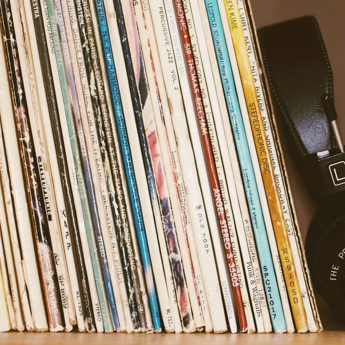 Placeholder: a shelf of vinyl records with headphones leaning against them.