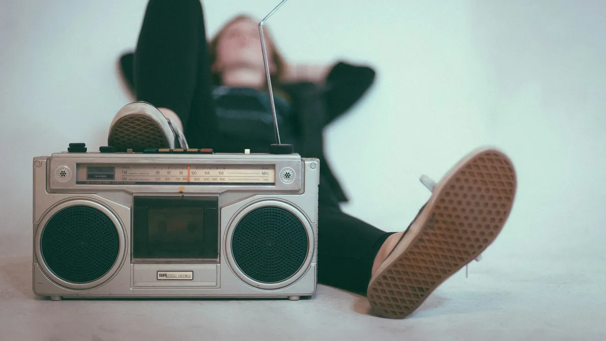 Placeholder: a person lying on the floor beside a boombox.